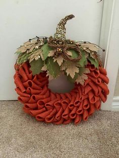 an orange wreath with leaves and berries on it