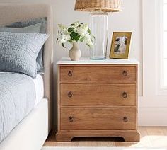 a bedroom with a bed, nightstand and pictures on the side table next to it