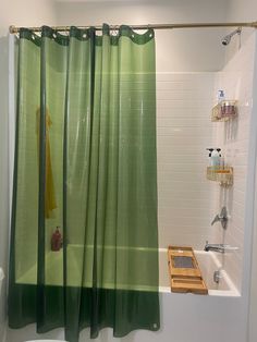 a green shower curtain in a bathroom next to a bathtub and shelf with items on it