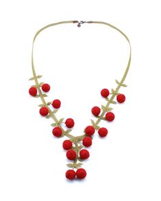 a necklace with red berries hanging from it's side on a white background,