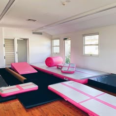 an empty room with pink and black mats on the floor, yoga mats are set up in front of windows