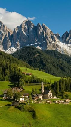 the mountains are covered in snow and green grass, with small houses on each side