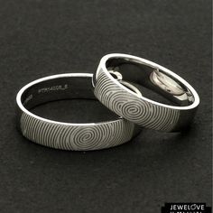 two wedding bands made to look like fingerprints on each other, one with a ring in the middle