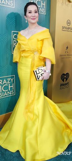 a woman in a yellow dress standing on a blue carpet with an award for best actress