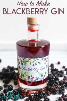 a bottle of blackberry gin sitting on top of a table with blackberries scattered around it