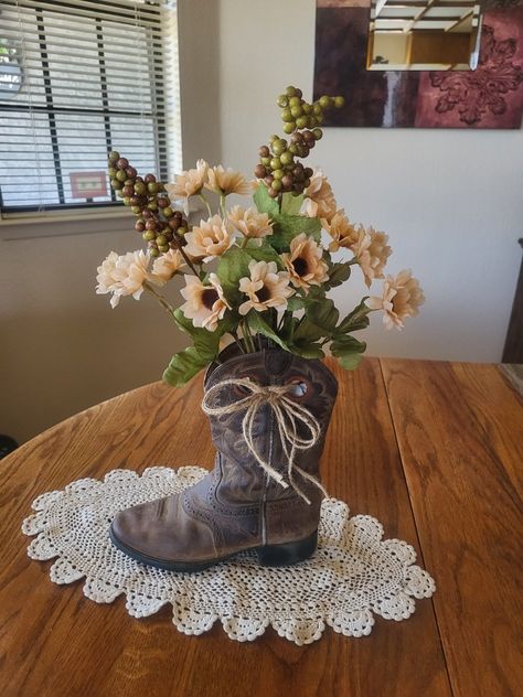 This is my 2nd decorated cowboy boot with flowers. Makes a nice rustic western look. The twine bow sets it off nicely. I stuffed the boot with heavy brown paper to keep it looking full and not tipping over. The doily gives it a nice country look. I love to upcycle/repurpose items. Boot Vase Centerpiece, Cowboy Boot Repurpose Ideas, Decorating With Cowboy Boots, Cowboy Boots Decor Ideas, Crafts With Cowboy Boots, Cowgirl Boot Flower Arrangement, What To Do With Old Cowboy Boots, Country Flower Arrangements Rustic Decor, Boots And Bowties Theme Party Ideas