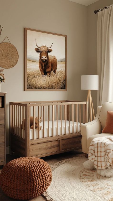 A rustic baby girl nursery with a natural wood crib, a Highland cow wall art, a rust-colored knit pouf, and a beige armchair. The design is completed with soft neutral tones, cozy textiles, and a round cream rug with fringe for a warm farmhouse-inspired atmosphere. Baby Girl Nursery Ideas, Girl Nurseries, Nature Themed Nursery, Girl Nursery Ideas, Nursery Inspiration Girl, Cow Nursery, Wood Crib, Knitted Pouf