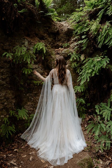 Inspired by ethereal forests of the Pacific Northwest where the trees are draped in mosses. Ivy gown is the ultimate blend of luxury and understated drama. Intriguing and totally unique, Ivy’s vine-like beading travels on your body like branches of a tree. Hand placed beaded appliques float on an illusion mesh bodice, draped with tulle, Ivy is an intricate masterpiece. A fitted beaded skirt is delicately layered with flowy tulle to let in a hint of sparkle throughout the dress, creating a multi Enchanted Forest Wedding Gown, Wedding Dress Mystical, Wedding Dress Forest Nature, Wedding Dress Whimsical Romantic, Whimsical Bridal Portraits, Lord Of The Ring Wedding Dress, Wedding Dresses Nature Inspired, Forest Witch Wedding Dress, Viking Wedding Ideas Dresses