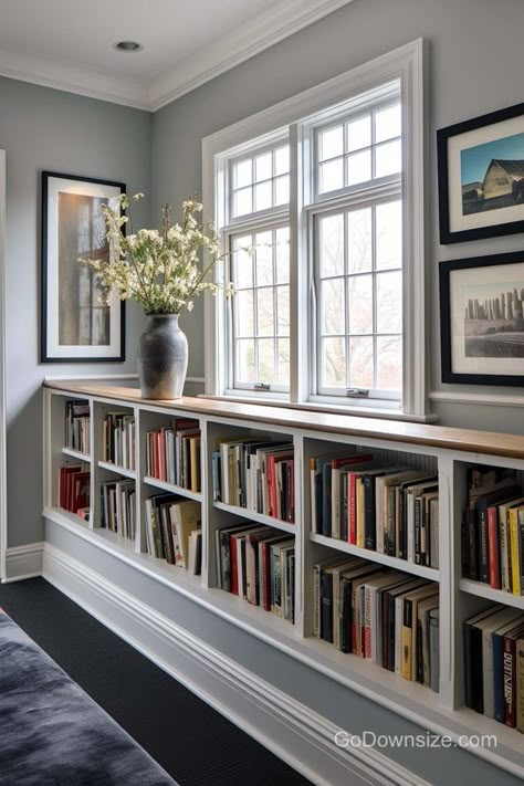 This lovely design enhances the window area with long rows of book storage to serve as a mini library. Windows Above Bookcases, Bookshelf For Study Room, Library In Hallway, Wainscoting Bookshelf, Built In Bookcase Under Window, Diy Bookshelf Around Window, Bookshelf Study Room, Mini Library In Living Room, Bookcase Window Wall