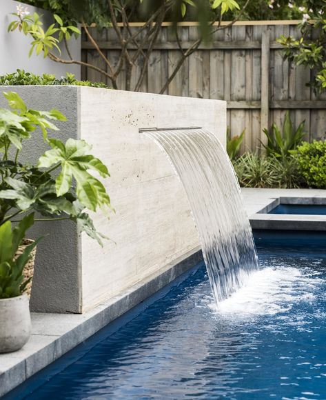 A travertine-clad water feature flows into the fibreglass swimming pool. Swimming Pool Fountains, Swimming Pool Waterfall, Pool Paving, Backyard Pool Ideas, Water Feature Wall, Travertine Pool, Pools Backyard Inground, Swimming Pool Landscaping, Pool Water Features