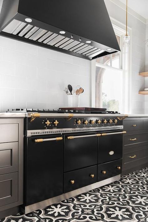 A Lacanche Range sits on a black and white cement floor tiles between black shaker drawers adorned with brass pulls and a white quartz countertop. French Stove, Lacanche Range, Modern Manor, Full House Remodel, Cement Floor Tiles, Farmhouse Kitchen Cabinets, Bathroom Redesign, Isamu Noguchi, White Quartz Countertop