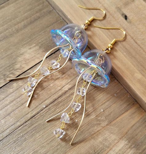 18k gold plated stainless steel handmade earrings of light blue aura jellyfish. These Jellyfish are made from dainty blue iridescent acrylic domes, glass crystal studded chain, and gold wisp tendrils.  The difference between these earrings and my popular Jellyfish earrings are the domes- unlike my green, teal, pink, and purple ones, these domes are made from a hard plastic so they are less fragile, and can be coated in the rainbow iridescent aura that is color shift depending on lighting and angle.  Please note that these earrings jingle similarly to my glass Jellyfish earrings that dangle. They are not too loud, and make a really cute jingly sound as you move. If you are sensitive to earrings making sound as you wear, then these earrings may not be for you. Thank you for your understandin Jelly Fish Earrings Diy, Cute Blue Earrings, Jelly Fish Earrings, Hand Made Earings, Jellyfish Outfit, Jellyfish Accessories, Jellyfish Jewelry, Jellyfish Earrings, Cute Jewellery