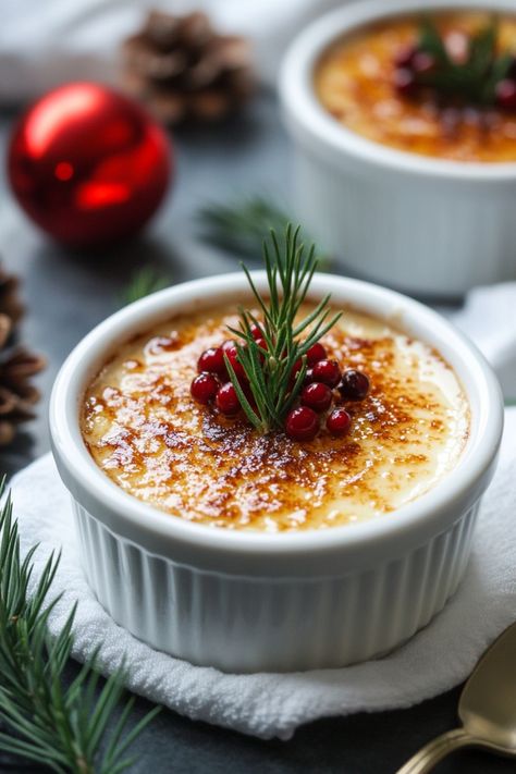 Creme brulee topped with red berries and a sprig of rosemary, surrounded by holiday decorations. Holiday Plated Desserts, Egg Nog Creme Brulee, Christmas Elegant Desserts, Eggnog Creme Brulee Recipe, Creme Brulee Christmas, Panna Cotta Christmas, Holiday Creme Brulee, Deserts In Cup, Christmas Dessert Elegant