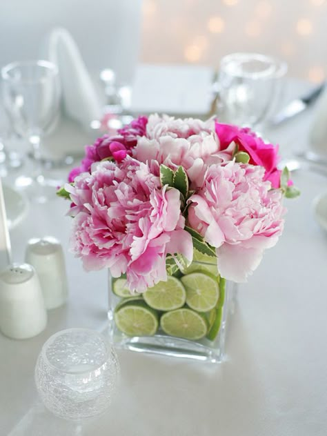 Flowers and Fruit:     Create a fragrant and colorful centerpiece with fresh lime slices and blooming perennials. The trick to keeping the lime slices upright is to use two vases of varying sizes, fitting one inside of the other and filling in the space with 1/4-inch-thick lime slices. The luscious fruit and floral scents will last for two to three days. Wedding Reception Table Decorations, Reception Table Decorations, Tafel Decor, Simple Centerpieces, Wedding Floral Centerpieces, Tea Party Decorations, Shower Centerpieces, Wedding Reception Tables, Brunch Wedding