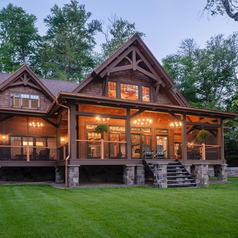 A deep wrap-around porch resting on stone pillars dominates the lakeside of this home overlooking a pristine Adirondack lake. Mountain House Wrap Around Porch, Stone House With Wrap Around Porch, Rustic House Plans With Wrap Around Porch, Homes With Big Porches, A Frame With Wrap Around Porch, Country House With Wrap Around Porch Farmhouse, Ranch Home Wrap Around Porch, Country House Designs Exterior, Rustic Wrap Around Porch