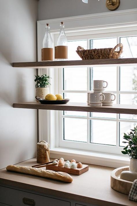 Stacked wood floating shelves are mounted in front of a window in a light gray kitchen pantry boasting light gray cabinets finished with vintage brass library pulls and a wooden countertop. Shelf In Window, Shelf Over Kitchen Window, Shelves In Front Of Window, Shelves Over Windows, Shelves In Front Of Kitchen Window, Shelf Over Window, Kitchen Window Shelf, Kitchen Window Design, Kitchen Floating Shelves