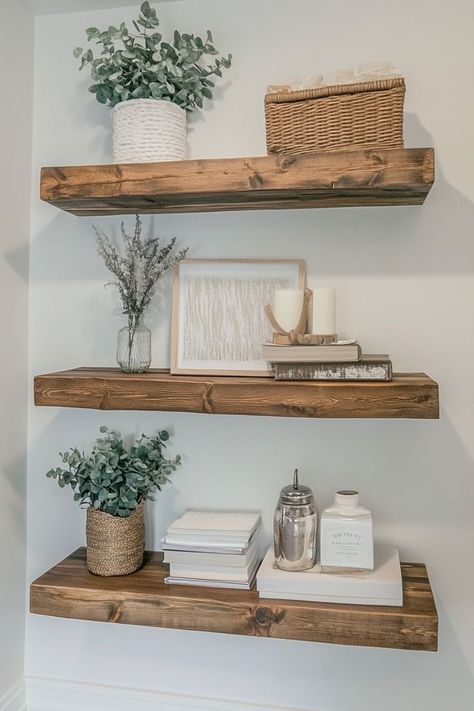 Use floating shelves to display aesthetically pleasing decor like candles, books, plants, and small framed art. To maintain a minimalist look, style the shelves with a limited number of items and ensure each piece complements the others in color and style. Great for living rooms, bedrooms, or kitchens.🛋✨ #FloatingShelves #StyledShelves #MinimalistDecor Wall Shelf Living Room Decor, Floating Shelves Styling Living Room, Plants On Shelves Living Room, Floating Shelves Placement Ideas, White Floating Shelves Living Room, 3 Floating Shelves Arrangement, Styling Floating Shelves Living Room, Floating Shelf Decor Bedroom, Floating Shelves Arrangement