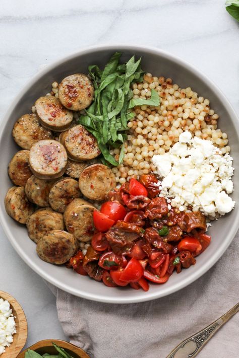 Garnished bowl of chicken sausage and bruschetta Sausage Bowl Healthy, Sundried Tomato Couscous, Chicken Sausage Salad Recipe, Chicken Sausage Couscous Recipes, Chicken Sausage Bowl Healthy, Sausage Bowl Recipes, Sausage And Couscous Recipes, Sundried Tomato Recipes Healthy, Chicken Sausage Bowls