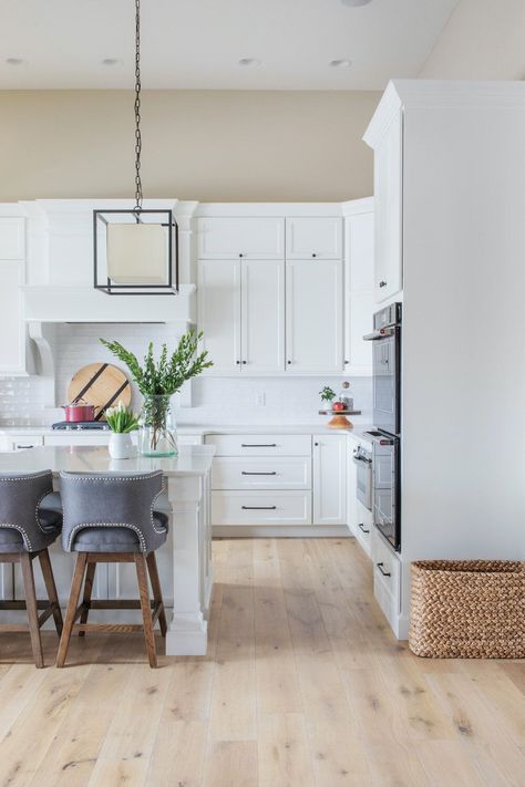 White Kitchen   White Oak Flooring   Fabric Bar Stools   Modern Kitchen   Tan Wall Paint   Box Pendant | Design by Scout Island Styling, Ruscus Greenery, Best White Paint Colors, Round Marble Table, Tan Walls, Italian Ruscus, Vintage Style Rugs, Light Hardwood, Best White Paint