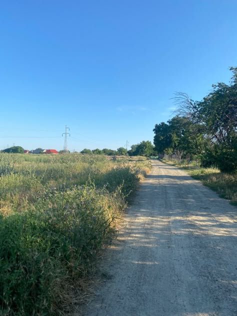 Image of a road in a small village area, surrounded by trees, bushes, flowers. The sky is clear and the sun is shining, suggesting a nice and warm temperature. European Childhood, Eastern European Summer, Eastern European Aesthetic, Europe Core, Small Town Summer, Eastern Europe Aesthetic, Small Town Aesthetic, Village Aesthetic, European Town