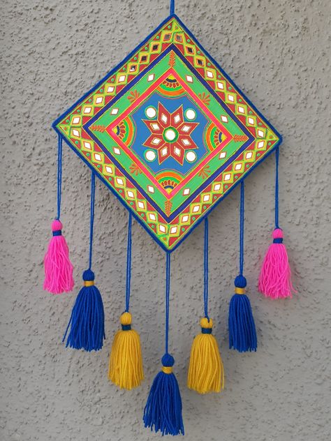 A simple, easy and colorful wall hanging craft idea. I have made it using waste cardboard. Painted it with acrylic colors and decorated with 3D outliners, yarn and some mirrors. This festive season add some colors to your home with this craft idea, its super easy to make. Wall Hanging Painting Ideas Canvas, Wall Decoration Craft Ideas, Cute Wall Hangings Diy, Home Made Wall Hanging, Mirror Work On Cardboard, Wall Hanging From Cardboard, Craft Hanging Decorations, Mirror Work Wall Hanging, Paper Craft For Decoration