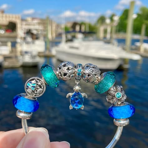 Happy Wednesday dear Pandora sisters!💙🩵💚😎 Today’s Ocean themed Pandora design at the Chelsea Harbor Marina features the lovely “Murano Glass Blue Sea Turtle” dangle charm as my centerpiece.🌊🛥️🐢 Included in my design are vintage classics from the Pandora Summer 2013 Collection, including a pair of the “Fascinating Aqua” muranos and the stunning silver “Sea Star”.💙🌊✨ I completed my styling with a pair of “Teal Shimmer” muranos, the “Ocean Life” charm and a pair of the silver Openworks with S... Pandora Ocean Charms, Pandora Ocean, Pandora Summer, Pandora Design, Blue Sea Turtle, Pandora Bracelet Ideas, Bracelet Ocean, Pandora Bracelet Charms Ideas, Pandora Murano