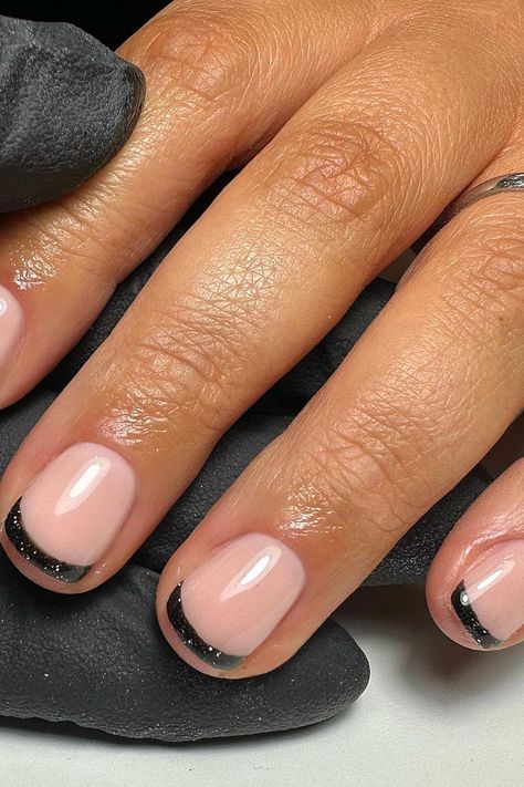 Elevate your nail game with these stunning glossy black glittery French tips on short squoval nails, blending timeless elegance with a contemporary edge. The soft pink base creates a delicate and natural aesthetic, while the bold black tip entices with a subtle sparkle, bringing a stylish modern twist to the classic French manicure! ✨ // Photo Credit: Instagram @kirstnailartist Dark Tipped Nails, French Dip Short Nails, French Tip Acrylic Nails Double Line, Black Gel Nails With Accent Nail, Alternate French Manicure, Black Glittery Nails Short, Anc Ombre Nails, How To Make Acrylic Nails Look Natural, Short Gel Nail French Tip