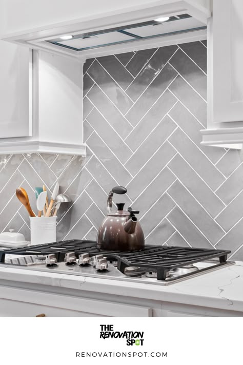 Kitchen Remodel by the Renovation Spot | Grey Herringbone Backsplash for White and Gold Kitchen Remodel | Modern Kitchen Design Light Gray Herringbone Backsplash, Modern Grey Kitchen Backsplash, Grey Herringbone Backsplash Kitchen, White And Grey Herringbone Backsplash, Kitchen Backsplash Grey And White, White And Grey Kitchen Backsplash Ideas, Kitchen Grey Tiles Wall, White Kitchen With Light Grey Backsplash, Dark Grey Herringbone Backsplash