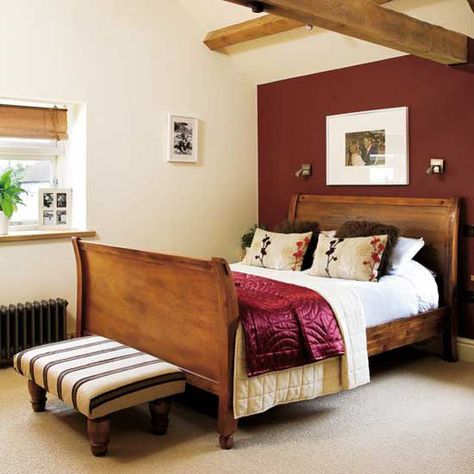 Wooden sleigh bed with striped footstool, beamed ceilings and red feature wall. Red Bedroom Walls, Red Feature Wall, Red Bedrooms, Red Bedroom Ideas, Red Apartment, Red Accent Wall, Feature Wall Bedroom, Bedroom Colour, Red Bedroom