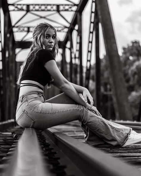 Black and white. Railroad bridge. Jeans and a black half shirt. Blonde girl sitting on railroad bridge. Photoshoot Railroad Tracks, Poses On Railroad Tracks, Photoshoot On Railway Track, Senior Pics On Train Tracks, Senior Picture Ideas On Railroad Tracks, Female Senior Picture Poses Photo Ideas, Railroad Track Photoshoot Senior Pics, Senior Picture Ideas At Night, Senior Railroad Pictures