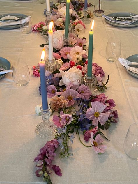 Pink purple blue pastel flower arrangement on dining table with candle sticks and blue ceramic dinner set for birthday dinner party Flower Aesthetic Birthday Party, Maximalist Table Decor, Flower Themed Party Aesthetic, Floral Party Table Decor, Circle Table Set Up, Flowers Laying On Table, Floral Dinner Table Setting, Flower Dinner Party Aesthetic, Flowers On Table Aesthetic