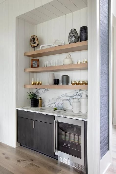 Well-appointed bar nook is fitted with floating blond wood shelves stacked against a white shiplap backsplash over black cabinets and a glass front beverage fridge fixed beneath a black and white marble countertop fitted against a black and white marble backsplash. Small Home Bar Ideas, Small Wet Bar, Wine And Coffee Bar, Small Bars For Home, Wet Bar Ideas, Bar Nook, Coin Bar, Home Wet Bar, Home Bar Rooms