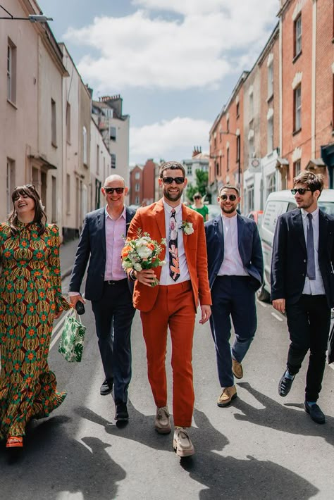 Groom in orange suit with patterned tie and white flower buttonhole and sunglasses walking with groomsmen in suits and sunglasses for Bristol city wedding Non Traditional Suit Men, Groom Colorful Suit, Fun Groom Suit, Mens Colored Suits Wedding, Funky Wedding Suits Men, Wedding Suits Men Colourful, Coloured Wedding Suit, Colorful Groom Attire, Men’s Wedding Suits 2023