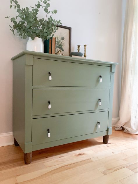 Traditional staging on sage green dresser with dark legs, white drop pulls, vintage print, vintage books, and greenery #painted #dresser #green Earth Tone Furniture Paint, Dresser Drawer Colors, Dresser Vintage Decor, Accent Color Dresser In Bedroom, Green Dresser Black Hardware, Dresser As Pantry, Sage Colored Furniture, Diy Dresser Makeover Sage Green, Green Dressers Bedroom