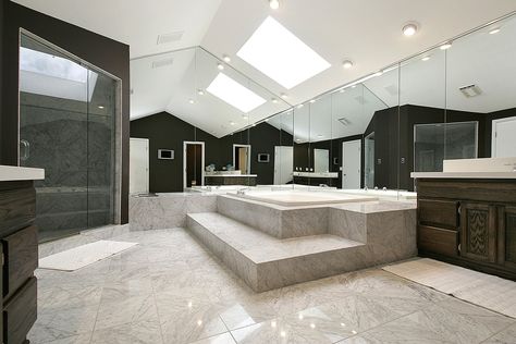 Immense, luxurious bathroom spreads marble tiling beneath a white vaulted ceiling. Full height mirrors on two walls add visual space, while natural wood cabinetry adds a traditional touch. Big Modern Bathroom, Skylight Bathroom, Advanced Yoga Poses, Luxury Bathroom Ideas, Bathroom Lighting Design, Bathroom Big, Modern Bathroom Interior, Black Interior Design, Decorating Bathroom