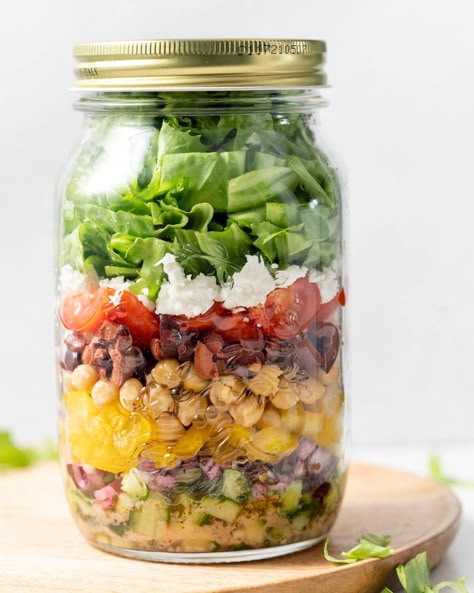 Ingredient for greek salad added so a large mason jar with lid over it Salad In A Jar Recipes Clean Eating, Chickpea Mason Jar Salad, Grinder Salad Mason Jar Recipe, Cobb Salad Mason Jar Recipe, Fruit Salad Meal Prep Mason Jars, Greek Salad In A Jar, Jar Greek Salad, Mason Jar Lunches, Jar Meal Prep