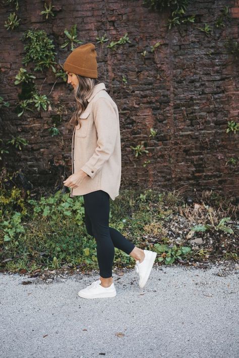 ashley wearing a tan shacket, black leggings, white sneakers, and brown beanie standing in front of a rock wall with green plants Casual Outfits Leggings Fall, Black Jeans And Shacket Outfit, Fall Airforce 1 Outfit, Cream Fleece Shacket Outfit, Shacket Outfit With Leggings, Brown Leggings Outfit Work, Comfy Shopping Outfit Fall, Casual October Outfits, Casual Shacket Outfits Leggings