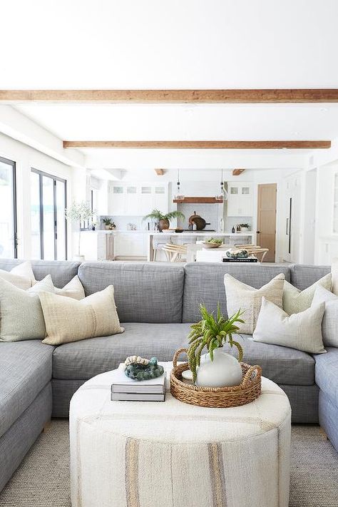 A round ivory ottoman coffee table sits on a gray rug in front of a blue-gray u-shaped sectional accented with ivory pillows. Ivory Ottoman, Ivory Pillows, Pure Salt Interiors, Pure Salt, Apartment Decoration, Grey Sectional, Cottage Living Rooms, Ottoman Coffee, U Shaped Sectional