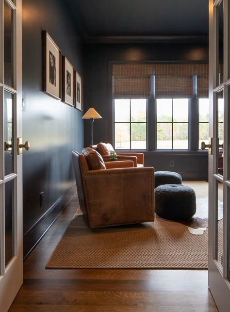 In his office we decided to paint the entire room including the built-in cabinetry and windows in Benjamin Moore Hale Navy This color was the neutral for this project We wanted this space to feel personal masculine and calm We incorporated a moody painting above the large desk space by one of our favorite local artists to give that added touch of masculinity We custom designed the roman shades in a mixed wood to add a touch of earthiness and surprised the homeowners by hanging black and white po Masculine Office Bookshelves, Masculine Sports Office, Masculine Roman Shades, Hale Navy Office Walls, Masculine Office Wallpaper, Hale Navy Room, Hale Navy Office, Navy Office Walls, Navy Home Office