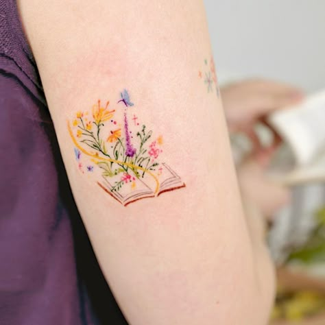 CafeMom.com : A Book Bursting With Color : 20 Beautiful Book Tattoos For Everyone's Inner Bookworm -- Here's a full-color book tattoo that's absolutely bursting with color. The quality of the texture of the ink seems inspired by woodblock paintings, with little to no line work and vibrant colors. This one also comes from Studio By Sol. Hip Tattoos Women Watercolor, Delicate Color Tattoo, Minimalist Colored Tattoo, Garden Tattoos For Women, Small Colorful Tattoos For Women, Inner Ankle Tattoos For Women, Small Color Tattoo, Small Book Tattoo, Book Lover Tattoo