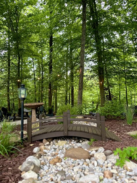 Dry creek bed in garden surrounding fire pit area. MY 2024 Small Bridge In Garden, Bed In Garden, Stream Landscaping, Landscape Island, Fairfield House, Dry Stream, Ground Level Deck, Creek Ideas, Wooded Landscape