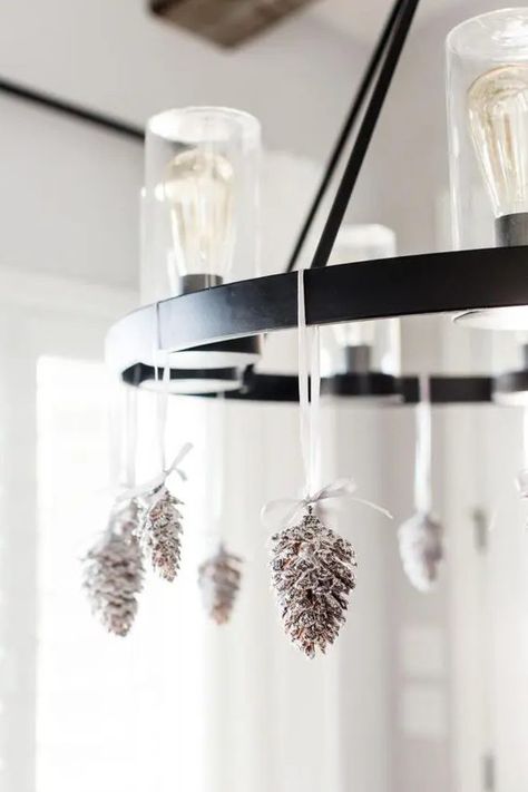 a bulb chandelier decorated with snowy pinecones is a cool and chic idea for the holidays, it's quite rustic Decorating A Chandelier, Zellige Tile Bathroom, Christmas Chandeliers, Christmas Chandelier Decor, Black Interior Door, Snowy Pinecone, Christmas Chandelier, Bulb Chandelier, Bathroom Chandelier