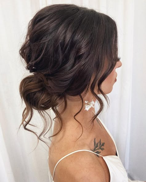 Charming Tousled Bun for Brides Messy Bun For Bridesmaid, Flowy Wedding Hairstyles Loose Updo, Bridesmaid Low Messy Bun, Loose Side Bun Wedding Hair, Low Bun With Front Pieces Curled, Low Bun Wedding Hair Dark Hair, Bridesmaid Hairstyles Messy Bun, Brown Bridesmaid Hair, Loose Curly Bun Wedding