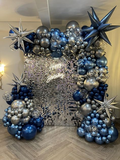 Why not add a touch of sheer enchantment to your party with our Silver Shimmer Wall? This dazzling display is perfect for birthdays, weddings, bar mitzvahs, corporate events and any other festivity you can think of. Your guests will be captivated by its dazzling glint and you'll love the pure enchantment that it brings to your event. We can even make it even better with a balloon garland! Silver And Blue Decorations Party, Silver And Blue Theme Party, Blue Birthday Theme Decorations, Shades Of Blue Theme Party, Navy And Silver Party, Silver Prom Decorations, Disco And Denim Party, Blue Silver Party, Blue Silver Birthday Party Decorations