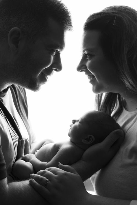 black and white image of Mum and Dad holding newborn baby girl and smiling at eachother New Born Parents Pictures, First Time Family Photos, New Born Baby Girl Photoshooting With Family, Baby Photo Shoot With Parents, Baby Photo With Parents, Family Portrait Newborn, Black And White Newborn Family Pictures, Studio Newborn Parent Poses, Couples Newborn Photoshoot