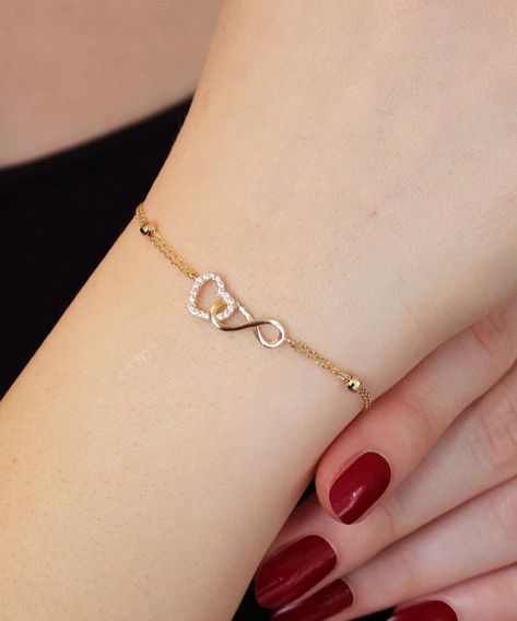 14K Gold Heart and Infinity Symbol Bracelet A symbol of infinite love, this elegant bangle bracelet showcases the symbols of love and eternity entwined with each other. The heart motif perfectly complements the infinity symbol for a truly romantic look. This unique bracelet is perfect for everyday wear as it is made of solid gold and won't tarnish. It is a wonderful gift for a special person. Features: * This bracelet is made of patented 14K solid gold. * It has a 16cm chain and 2cm charm Heart And Infinity Necklace, Hand Wear Accessories, Infinity Heart Bracelet, Gold Heart Bracelet For Women, Simple Hand Bracelet, Women’s Bracelets Gold, Beautiful Bracelet Gold, A Bracelet Gold, Bracelet Design For Girls In Gold