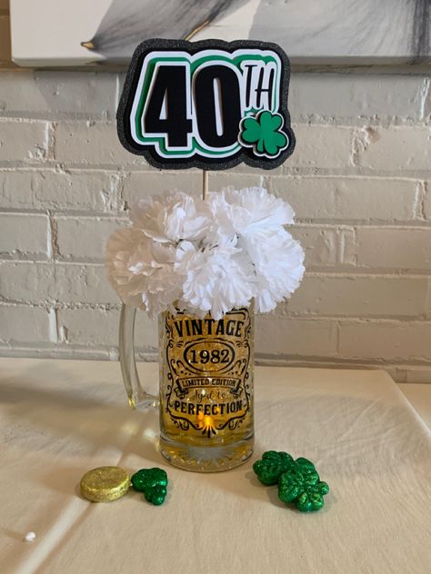 Dollar store mug, flower, shamrock & gold coins. 
Black vinyl and stencil on cricut
40th sign made out of layered card stock using cricut. Filled with colored water and added clear water beads from Craft store. Aged To Perfection Party Centerpieces, 40th Bday Centerpieces For Men, 40th Birthday Ideas For Men Centerpieces, Masculine Birthday Party Centerpieces, Beer Centerpieces For Men Party, Masculine Centerpieces Birthday, Men Birthday Centerpiece Ideas, Diy 50th Birthday Centerpieces, 30th Birthday Centerpieces For Men