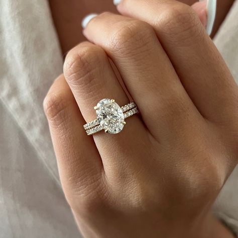 This exquisite engagement ring set showcases a brilliant 3-carat oval lab-grown diamond, complemented by the shimmering beauty of pave-set diamonds. The oval diamond radiates exceptional quality with its brilliant cut facets, while the hidden halo design frames it with smaller accent diamonds, creating a mesmerizing effect. The band itself is adorned with french pave diamonds, adding a sparkling brilliance that enhances the ring's overall allure. Each diamond is securely set in a shared prong se Two Wedding Bands With Engagement Ring Bridal Sets, Oval Cut Engagement Ring Diamond Band, Harmony Jewels London, French Pave Oval Engagement Ring, Rose Gold Wedding Ring Oval, Oval Engagement Ring With Accent Band, Oval Shaped Engagement Rings White Gold, Raised Oval Engagement Ring, 2 Carat Oval Wedding Ring Set