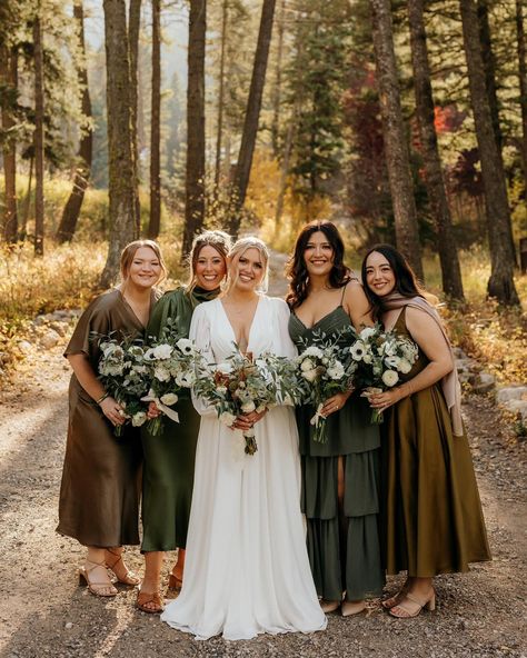 Bride and bridesmaids stand close together smiling at camera Mix Matched Fall Bridesmaid Dresses, Boho Fall Wedding Bridesmaid Dresses, Green Wedding Family Photos, Bridesmaids In Different Shades Of Green, Woodsy Bridesmaid Dresses, Fall Wedding Olive Green, Green And Brown Bridesmaid Dresses, Green And Brown Wedding Party, Forest Green Bridesmaid Dresses Fall