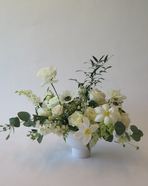 Our large centerpieces are elegant arrangements featuring a burst of luxe, seasonal flowers and accents of foliage. These are perfect on round tables or rectangular tables (we would recommend two for a rectangular table). The vases are included in the price of this design and are yours to keep after your wedding. Things you need to know: We need a minimum of 7 days notice for grab & go floral orders Your order must be between $1,000 - $3,000 in order to be finalized All arrangements in your order must come from the same color palette collection (ie: white & green) All Grab & Go orders are pickup ONLY - no delivery or setup is available Calla Lily Wedding Centerpiece Flower Arrangements, White And Green Arrangements, White Floral Arrangements Centerpieces, Wedding Floral Centerpieces Round Table, Winter Flower Arrangements Centerpieces, White Urn Arrangement, White Centerpiece Flowers, Large Wedding Arrangements, White And Gold Flower Arrangements